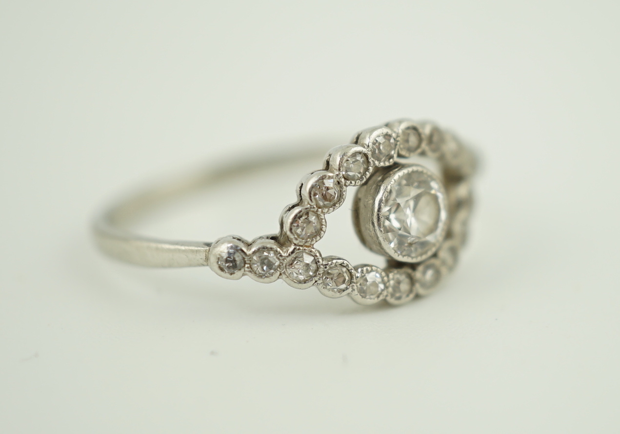 A white metal and single stone elliptical shaped ring, with diamond set border and shoulders, size M, gross weight 2.1 grams.